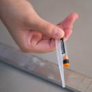 hand holding a vial and pipette bulb used to collect samples for the UC Davis COVID-19 testing process